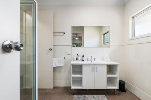 a white bathroom with a sink and a shower at Charming 2BR Home in Serene Mount Warren Park in Windaroo