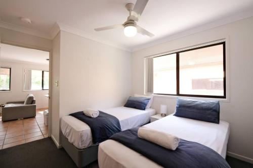 Coastal 2BR Retreat Heart of Broadbeach Living في غولد كوست: غرفة نوم بها سريرين ونافذة