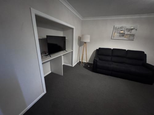 a living room with a black couch and a television at Apartments on Turf Unit 4 in Grafton