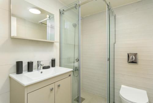 a bathroom with a sink and a glass shower at Curl 2-Bedroom Apartment in Gemmayzeh in Ar Rumayl
