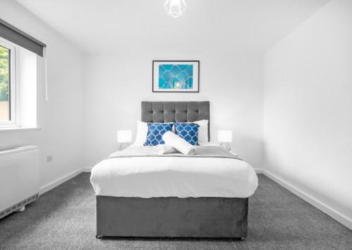 een witte slaapkamer met een groot bed met blauwe kussens bij Cozy 2 Bed Apartment - Parking - Netflix 27AC in Sleightholme