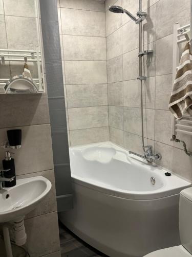 a bathroom with a tub and a toilet and a sink at Vecpilsētas apartaments in Cēsis