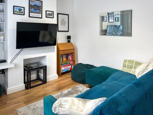 a living room with a blue couch and a tv at Miner's Rest in Rowrah