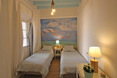 ein Zimmer mit zwei Betten und einem Gemälde an der Wand in der Unterkunft Marina 48 Seafront Apartment in Port de Sóller