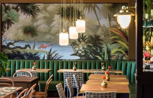a dining room with tables and a wall with a mural at Hotel Eco Boutique Bidasoa in Santiago