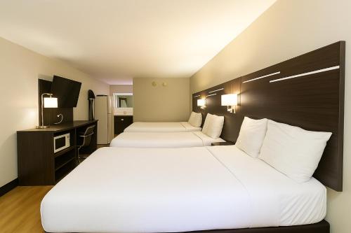 two beds in a hotel room with white sheets at Paragon Inn Hillsboro in Hillsboro