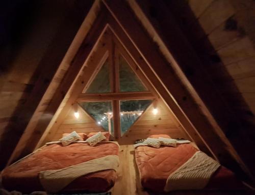 two beds in a room with a window at Cabaña Familiar in Jilotepec