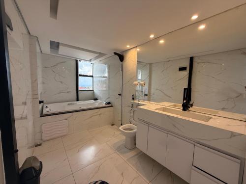 a white bathroom with a tub and a toilet at Pousada Bela Flor in São Thomé das Letras
