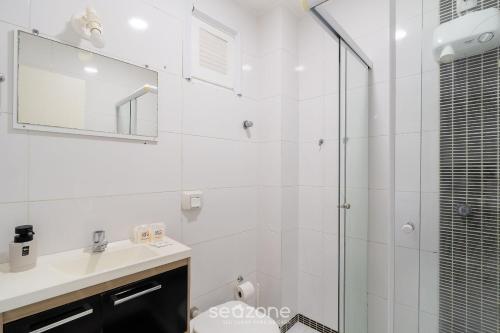 a bathroom with a shower and a sink and a mirror at Aptos em prédio a 500m da Praia de Canasvieiras - GALs in Florianópolis
