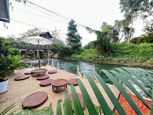 a patio with tables and chairs next to a river at Wang Namthip Hotel in Muang Fuang