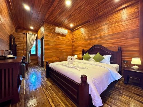 a bedroom with a large bed in a wooden room at Wang Namthip Hotel in Muang Fuang