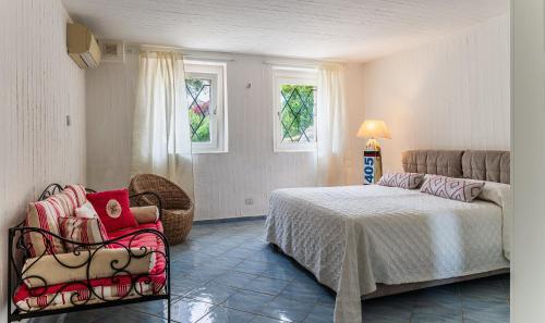 een slaapkamer met een bed, een stoel en ramen bij Li Conchi 33 in Cala Sinzias