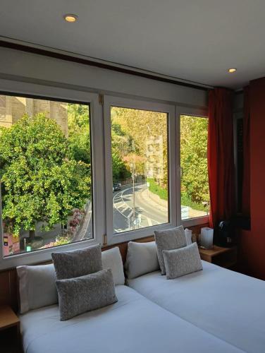 a bedroom with a white bed and two windows at Ekia Pentsioa in Zarautz