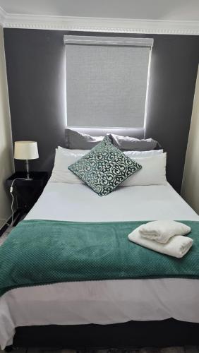 a white bed with a green blanket and a pillow at The cosy haven nr 2 in Harrismith
