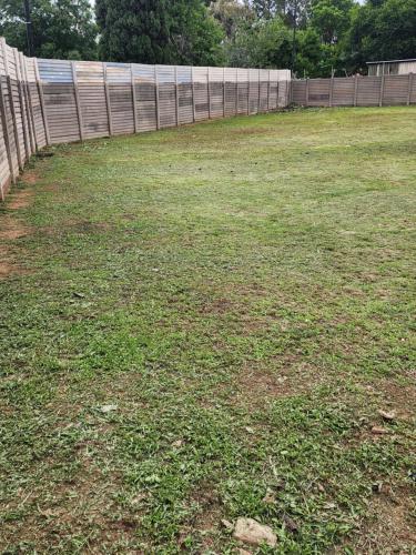 een tuin met een hek en een grasveld bij Tk guesthouse in Sasolburg