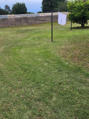 een grasveld met een hek op de achtergrond bij Tk guesthouse in Sasolburg