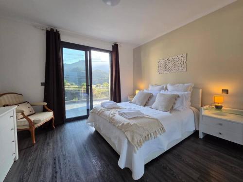 a bedroom with a white bed and a large window at Cottage Bela Vista by Escape to Madeira in Cedros