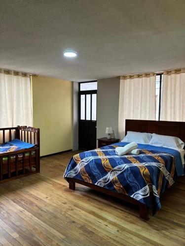 ein Schlafzimmer mit einem Bett mit einer blau-gelben Decke in der Unterkunft Jacquelins house in Baños