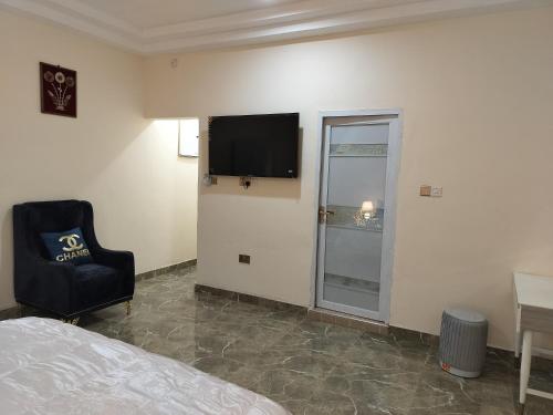 een slaapkamer met een bed, een stoel en een televisie bij Modern 1 bedroom flats in Tema