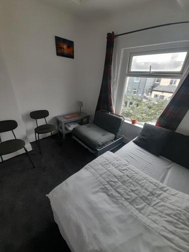 a bedroom with a bed and a window and a chair at Canton Principality Stadium Studio Flat in Cardiff