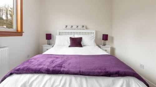 a bedroom with a purple blanket on a bed at Sea The View in Rothesay