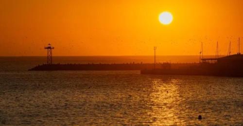 a sunset over a body of water with a pier at Gemma in Mossel Bay
