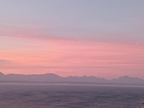 a sunset over the ocean with mountains in the background at Gemma in Mossel Bay
