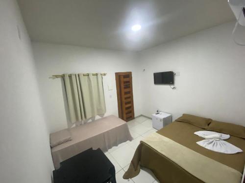 a small room with two beds and a television at Sol Dos Lençois Pousada in Barreirinhas