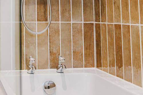eine Badewanne mit zwei Armaturen im Bad in der Unterkunft Wisteria Cottage 3 Bed Garden & Free Parking in Kenilworth
