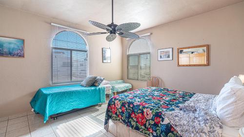 a bedroom with a bed and a chair and a ceiling fan at Cypress House in Puerto Peñasco