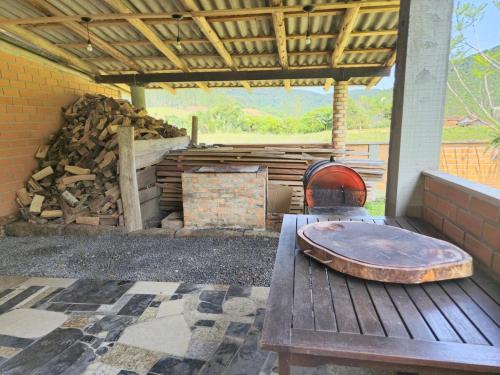 a wooden table sitting on a porch with a pile of wood at Sito São Joaquim in Itaquá