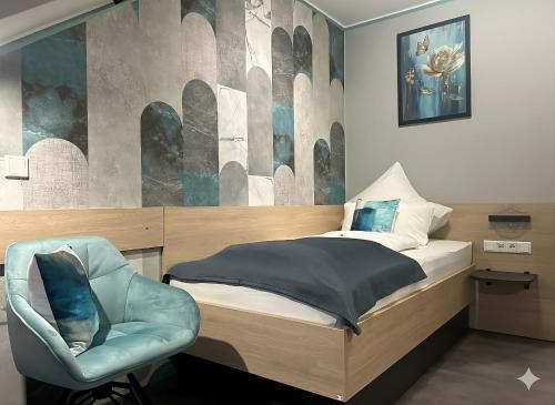 a bedroom with a bed and a blue chair at Flair Hotel zur Therme in Erwitte