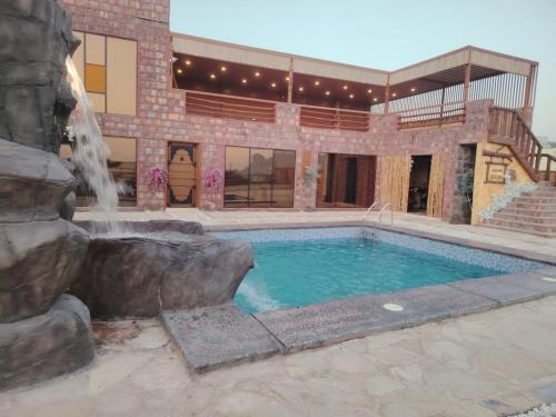 a swimming pool with a waterfall in front of a building at كهف الريف Reef Cave in Al Ḩamrāʼ