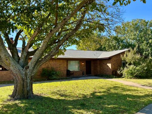 a brick house with a tree in the yard at Spacious Arcade Table Tennis Game Room Cowboy Pool Near Tx Motor Speedwayby Vacation Your Way in Fort Worth