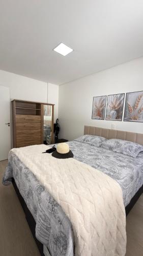 una camera da letto con un grande letto con un cappello sopra di Apto Flor Três Marias-2 Quartos- Apto todo climatizado- Moderno, confortável, à 150m do Parque Termal a Piratuba