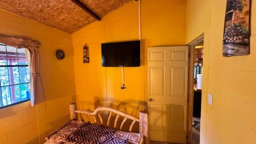 a yellow room with a chair and a tv on the wall at Villa Josefina in Santiago Sacatepéquez
