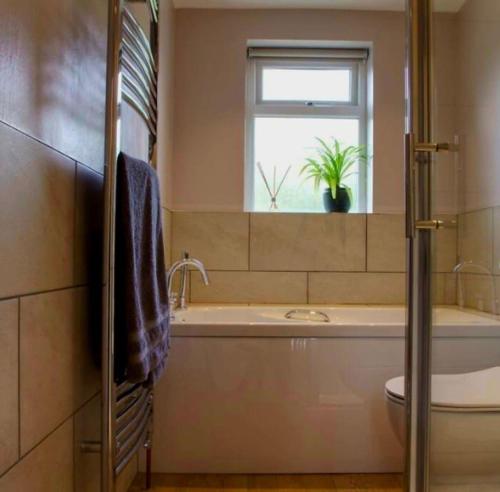 a bathroom with a tub and a sink and a window at Nikolaus Cottage Cotswolds in Winchcombe