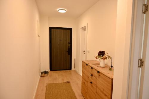 a hallway with a wooden dresser and a black door at Hanan Apartmani in Novi Pazar