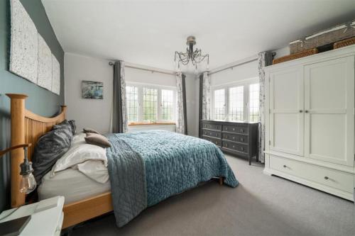 a bedroom with a bed and a dresser and windows at Cyclists Rest Matlock in Matlock