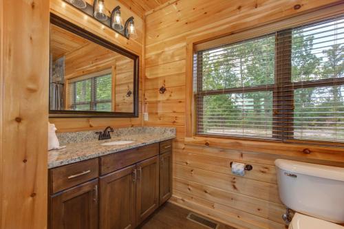 Un baño de cabaña de madera con lavabo y espejo. en Majestic View, en Williamsburg