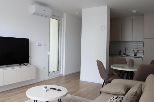 Una sala de estar con un sofá, un televisor y una mesa. en Il sogno apartman, en Vranješ