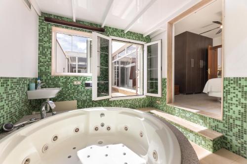 a bath tub in a bathroom with green tiles at Serenity Villa Lanzarote by Beyond in San Bartolomé