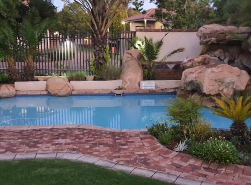 a swimming pool with a waterfall in a yard at Trinity S t a y in Benoni