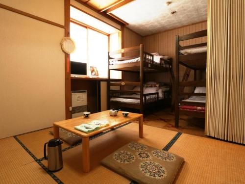 a room with a room with bunk beds and a table at Lodge Yukiyama in Nozawa Onsen