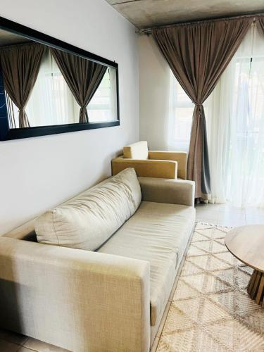 a living room with a couch and two windows at Felinga Guest House in Centurion