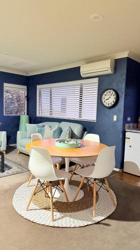 a dining room with a table and chairs and a couch at Beach Apartment in Papamoa