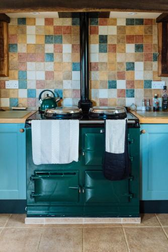 a green stove in a kitchen with towels on it at Hogchester Cottage in Bridport