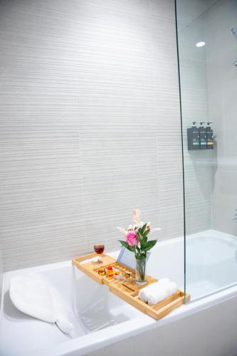 a bathroom with a bath tub and a tray with flowers at Yas Golf Elegant Studio near Ferrari World in Abu Dhabi