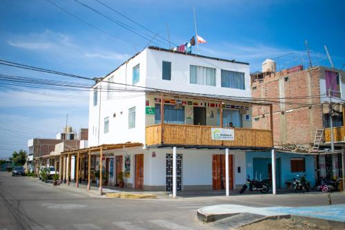 a white building on the corner of a street at HOSPEDAJE WELCOME PARACAS peru in Paracas