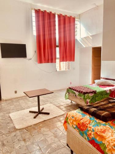 a room with two beds and a table in it at Hotel Cetro in Belo Horizonte